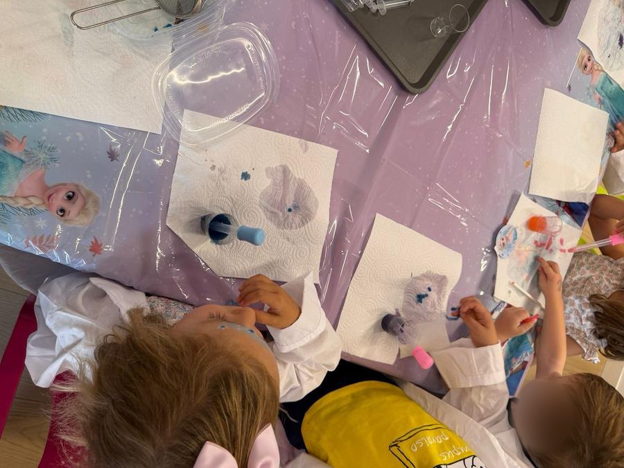 Niños con batas en la mesa de experimentos