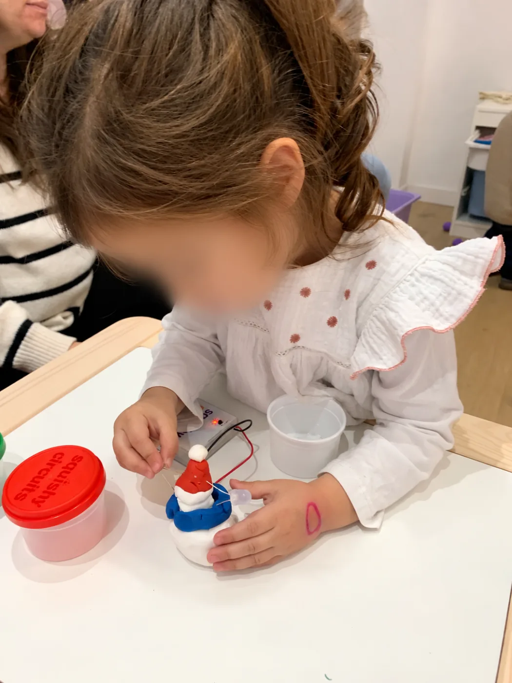 Niña montando un circuito con plastilina conductora y una luz LED
